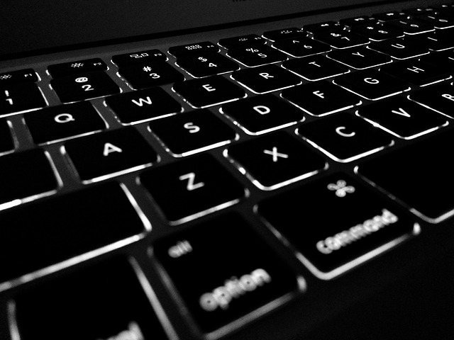 close-up of hands typing on laptop with organized desktop and notebook